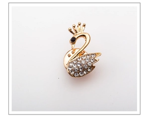 Macro view of gold swan brooch with sparkling crystals and black gemstone eye detail