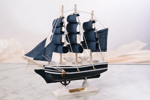 Vue détaillée du modèle de voilier en bois méditerranéen avec voiles bleues et socle blanc