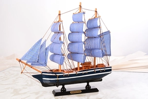 Détail d'un voilier miniature en bois avec des voiles à rayures bleues et blanches et plaque