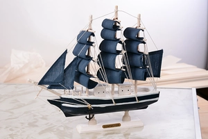 Détail d'un modèle de voilier en bois méditerranéen avec voiles bleues et plaque Confection