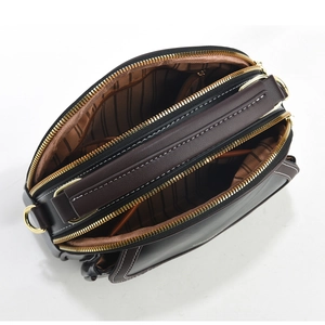 Detailed view of the three-layered interior compartments with gold zippers and striped lining