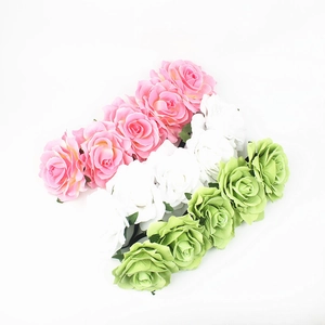 Close-up of artificial fabric roses in pink, white, and green for bohemian headbands
