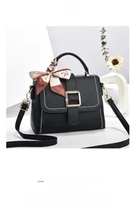 Detail of black textured PU leather bag with white stitching and gold metal buckle