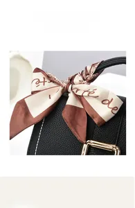 Close-up of black lychee leather handbag featuring a gold buckle and printed silk scarf