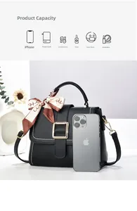 Detail of black pebbled leather crossbody bag with gold buckle and silk scarf handle
