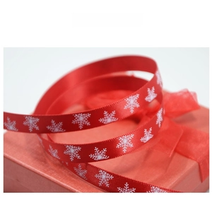 Macro view of red Christmas ribbon with white snowflake patterns on a festive gift box