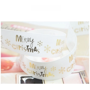 Macro shot of white grosgrain Christmas ribbon with Merry Christmas gold foil prints