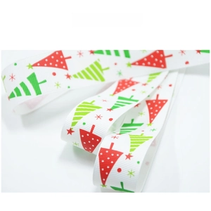 Detailed view of white Christmas ribbon with red stars and green tree patterns