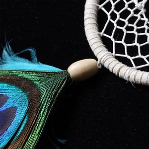 Macro detail of natural peacock feathers and wooden bead on a handmade dream catcher