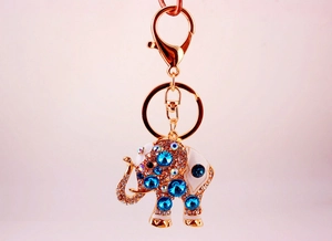 Detailed view of golden elephant keychain with sparkling blue crystals and white enamel