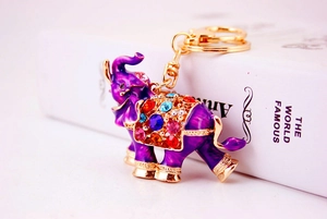 Close-up of golden elephant keychain with purple enamel and colorful rhinestones on a book
