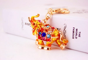 Close-up of golden elephant keychain with colorful rhinestones on a book background