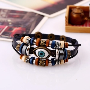 Detail of multi-layer leather bracelet with blue evil eye bead and bronze metal accents
