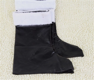 Top-down view of black Santa boots featuring white faux fur trim on a beige carpet