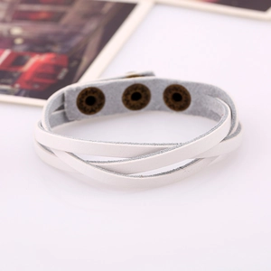 Detail of white multi-layer leather bracelet with bronze vintage snaps on white surface