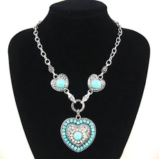 Detail of bohemian heart necklace with turquoise stones on a black neck bust display