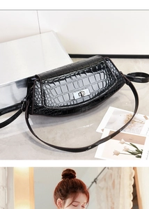 Detail of black crocodile texture patent leather handbag with silver rotary buckle