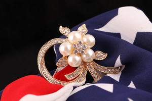 Macro shot of gold floral brooch with white pearls and sparkling crystal rhinestones