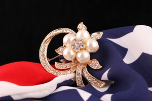Macro shot of a vintage gold floral brooch featuring white pearls and rhinestones