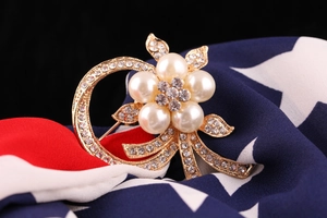 Macro shot of elegant floral pearl brooch with gold finish and sparkling rhinestones