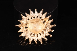 Detailed back view of a golden flower brooch showing the horizontal pin fastener
