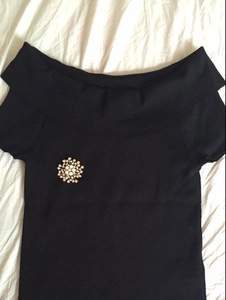 Detailed close-up of a flower cluster brooch with white pearls on a black knitted top