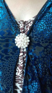 Close-up of a floral pearl brooch with rhinestones on a navy velvet cardigan