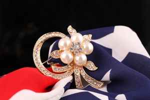 Close-up of golden flower brooch with white pearls and sparkling rhinestones