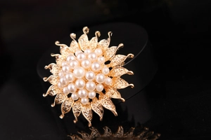 Macro shot of a golden sunflower brooch with detailed petals and cluster of white pearls