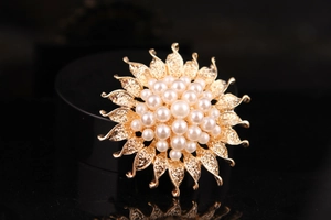Detailed view of sunflower brooch with golden petals and clusters of white pearls