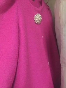 Detail of elegant pearl and rhinestone flower brooch pinned on textured wool fabric