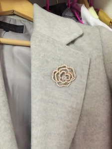 Detail of elegant camellia flower brooch with pearls and crystals on a grey coat lapel