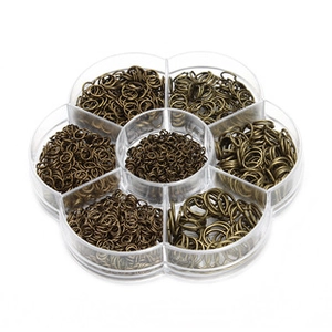 Detailed view of assorted bronze jump rings in a transparent multi-grid organizer box