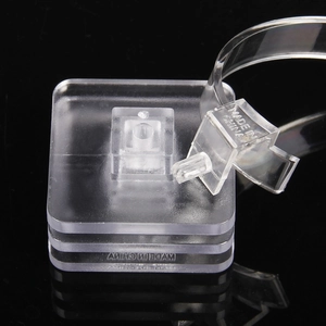 Clear acrylic watch display stand with modular base on a dark professional background