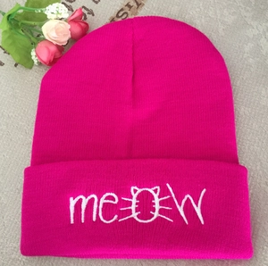 Close-up of Meow embroidery on rose red knitted beanie with feline motif detail