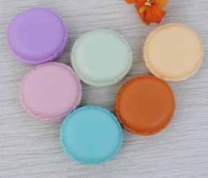 Detailed view of colorful macaron-shaped mini jewelry storage cases on a wood background