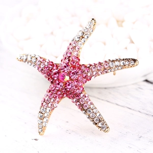 Starfish brooch with pink and white rhinestones on a minimalist white wooden surface