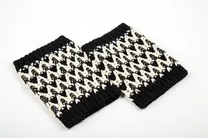Dettaglio degli scaldamuscoli in maglia con motivo geometrico a zig-zag bianco e nero