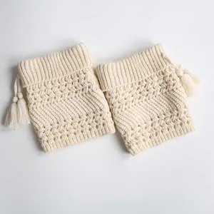 Creamy white knitted leg warmers with hollow patterns and fringe tassels in retro style