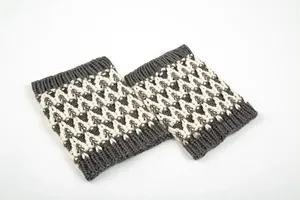 Dettaglio degli scaldamuscoli in maglia a onde grigio scuro e bianco crema