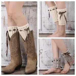 Detail of cable knit boot cuffs with vintage buttons and bows on wooden background