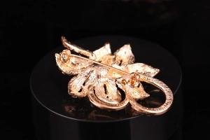 Macro detail of gold floral brooch back with secure rotating safety pin clasp mechanism