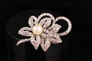 Macro shot of silver flower brooch with large white pearl and sparkling crystals