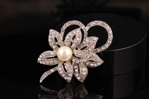 Macro view of silver floral brooch featuring crystal petals and a large center pearl