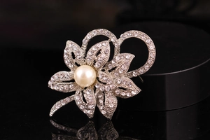 Macro view of silver floral brooch with sparkling rhinestones and a large center pearl