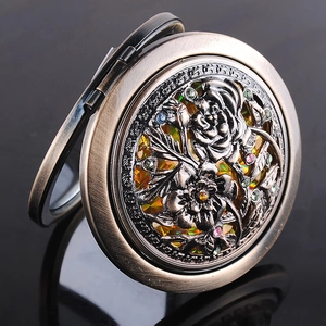 Detail of vintage bronze folding makeup mirror with hollow flower carving and colorful rhinestones