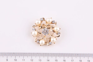 Dettaglio di una spilla a ghirlanda con perle e cristalli con base dorata da 4,5 cm