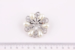 Dettaglio della spilla a corona con perle e cristalli con scala di misura da 4cm