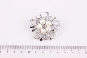 Dettaglio di una spilla a fiori argento da 4,5 cm con perle e cristallo su sfondo bianco