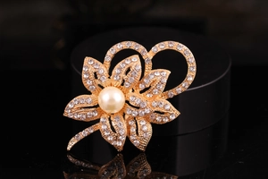 Detail of silver alloy flower brooch with large pearl and sparkling crystals on dark stand